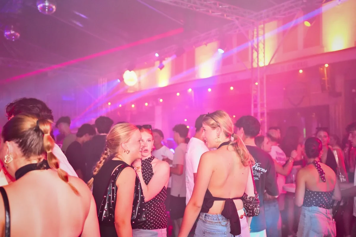 Volle dansvloer in roze en paars licht